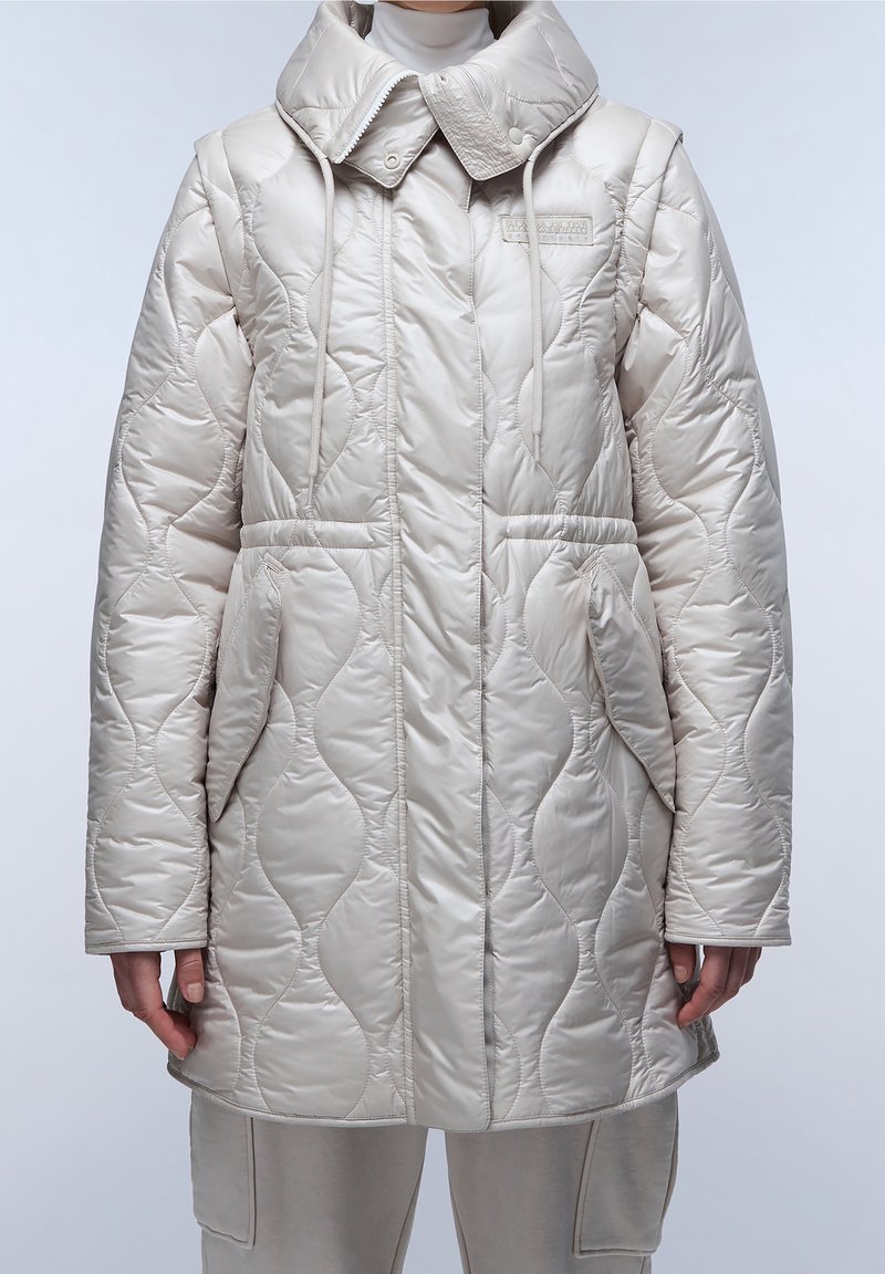 Béžová prošívaná bunda s vysokým límcem, stahovacími šňůrkami a dvěma předními kapsami. Materiál má lesklý povrch s vlnovým vzorem.