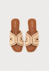 Beige flate mules med vevd mønster og dekorative metallakenter. Polstret brun såle og firkantet tådesign.