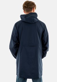 Veste marine imperméable avec capuche, manches longues et coupe décontractée ; dotée d'une poche à l'arrière et d'une texture lisse.