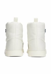 Botas tobilleras estilo puffers blancas con una superficie texturizada, que presentan una suela gruesa, una lengüeta trasera y el logotipo "RESISTENTE AL AGUA" en el costado.