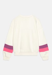 Sudadera de color crema con mangas largas que presenta rayas horizontales en rosa, púrpura y marrón en los puños. Tela suave y corte relajado.