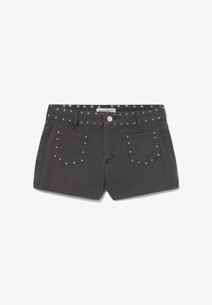 Pantalones cortos de mezclilla negra con bolsillos delanteros y detalles de tachuelas plateadas en la cintura, bolsillos y trabillas del cinturón.