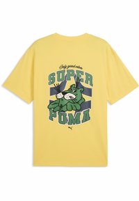 Żółta bawełniana koszulka z krótkim rękawem, na której znajduje się duży zielony grafik z rysunkowym kotem oraz tekstem "SUPER PUMA" i "Tylko dobre wibracje" powyżej.