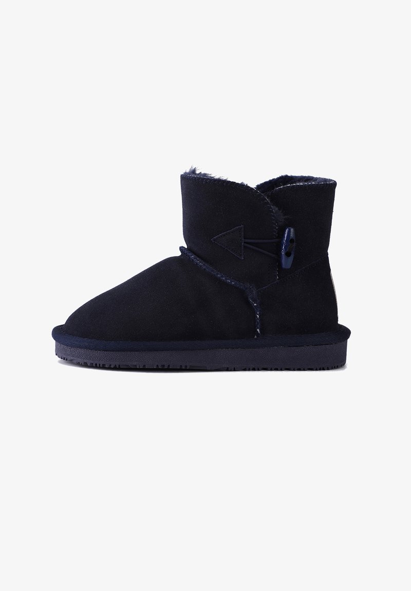 Botas de tobillo de ante azul marino con forro de piel suave, cuello en ángulo y botón decorativo. Suela de goma con patrones de tracción.