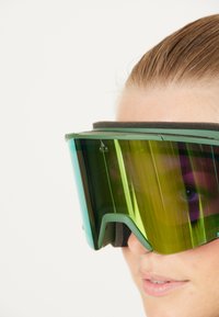 Lunettes de ski vertes avec un grand design incurvé, dotées d'un verre réfléchissant jaune-vert et d'un rembourrage noir le long du bord intérieur de la monture.