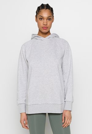 Grijze hoodie met een voorzak, verstelbare koord en raglanmouwen. Zachte textuur en een ontspannen pasvorm. Gepaard met groene leggings.