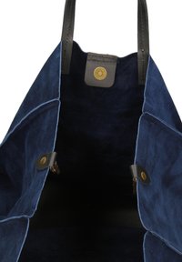 Marine suède tote bag met zwarte leren handvatten en messing drukknoopsluitingen. Glad oppervlak met een ruime binnenkant, zonder zichtbaar logo of versieringen.