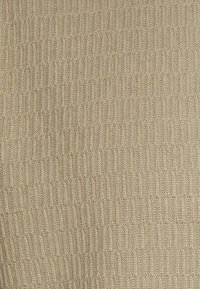 Tessuto beige testurizzato con un motivo a coste, caratterizzato da linee verticali equidistanti e un aspetto morbido e lavorato a maglia.