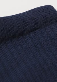 Tissu tricoté bleu marine avec une texture côtelée, mettant en valeur des coutures fines et un design de poignet sans couture.