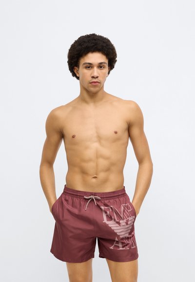 Bordó fürdőnadrág elasztikus derékrésszel és húzózsinórral. Oldalán világos logónyomattal, sima, vízlepergető anyagból készült.