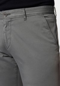 Šedé bavlněné chinos kalhoty s hladkou strukturou, s knoflíkovým zapínáním, bočními kapsami a jemnými švy. Vystřihnutý střih.