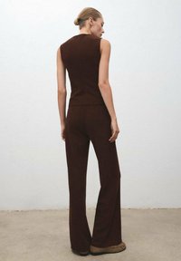 Brown sleeveless top and matching flared pants made of ribbed fabric. The outfit features a fitted design with a smooth texture.
