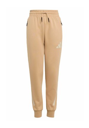 Jogging beige avec une taille à cordon, des poches latérales et un logo réfléchissant sur la cuisse gauche. Tissu doux avec des poignets effilés.