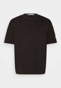 T-shirt in cotone nero con colletto rotondo e maniche corte. Dettaglio notevole: piccolo logo ricamato sulla manica sinistra.