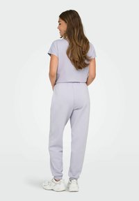 Lichtpaarse cropped t-shirt en bijpassende joggerbroek, gemaakt van zachte stof. De joggerbroek heeft elastische boorden bij de enkels en een relaxte fit.