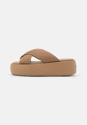 Beige plateau sandaal met dikke, gevlochten kruisbanden en een gewatteerde zool, zijaanzicht op een effen witte achtergrond.