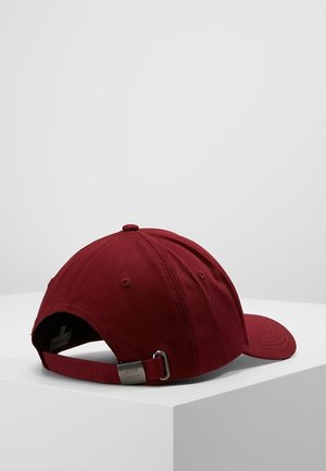 Mørkerød baseballkasket med justerbar metalspænde, vist på en hvid overflade mod en ensartet lys grå baggrund.