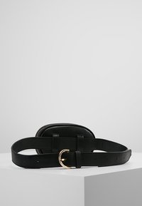 Borsa a tracolla in pelle nera con fibbia dorata, pochette ovale e tracolla regolabile, esposta su una superficie bianca con uno sfondo grigio.