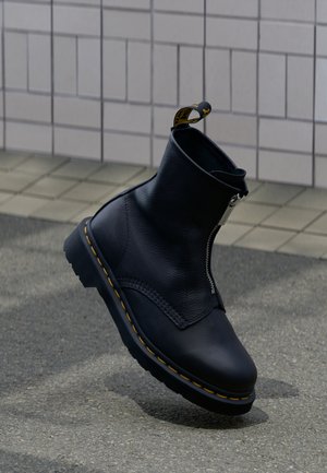 Μαύρο δερμάτινο μποτάκι αστραγάλου με πλαϊνό φερμουάρ, υφή επιφάνειας, κίτρινη διακοσμητική ραφή και λαστιχένια σόλα.