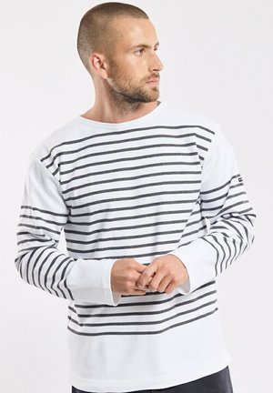 Chemise à manches longues blanche avec des rayures horizontales gris foncé, fabriquée en tissu doux. Dotée d'un col rond et de poignets côtelés.