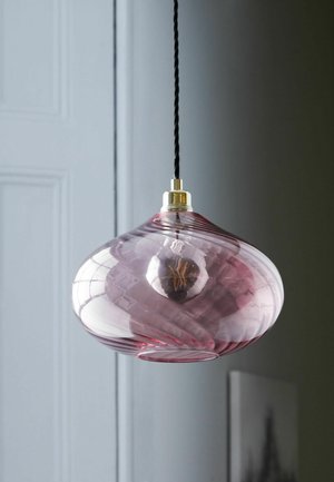 Suspended pink glass pendant lamp with twisted design and visible filament bulb inside, hanging against a plain wall background.