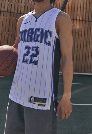 Persoon draagt Orlando Magic basketbalshirt nummer 22 en houdt een Spalding basketbal vast op een buitenveld.