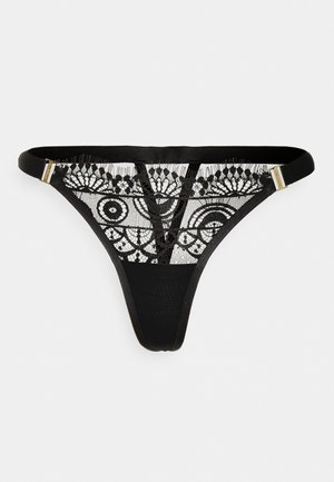 Tanga preta com painel de renda apresentando padrões circulares e detalhes delicados. Alças finas e acabamentos em tom dourado. Textura de tecido suave.