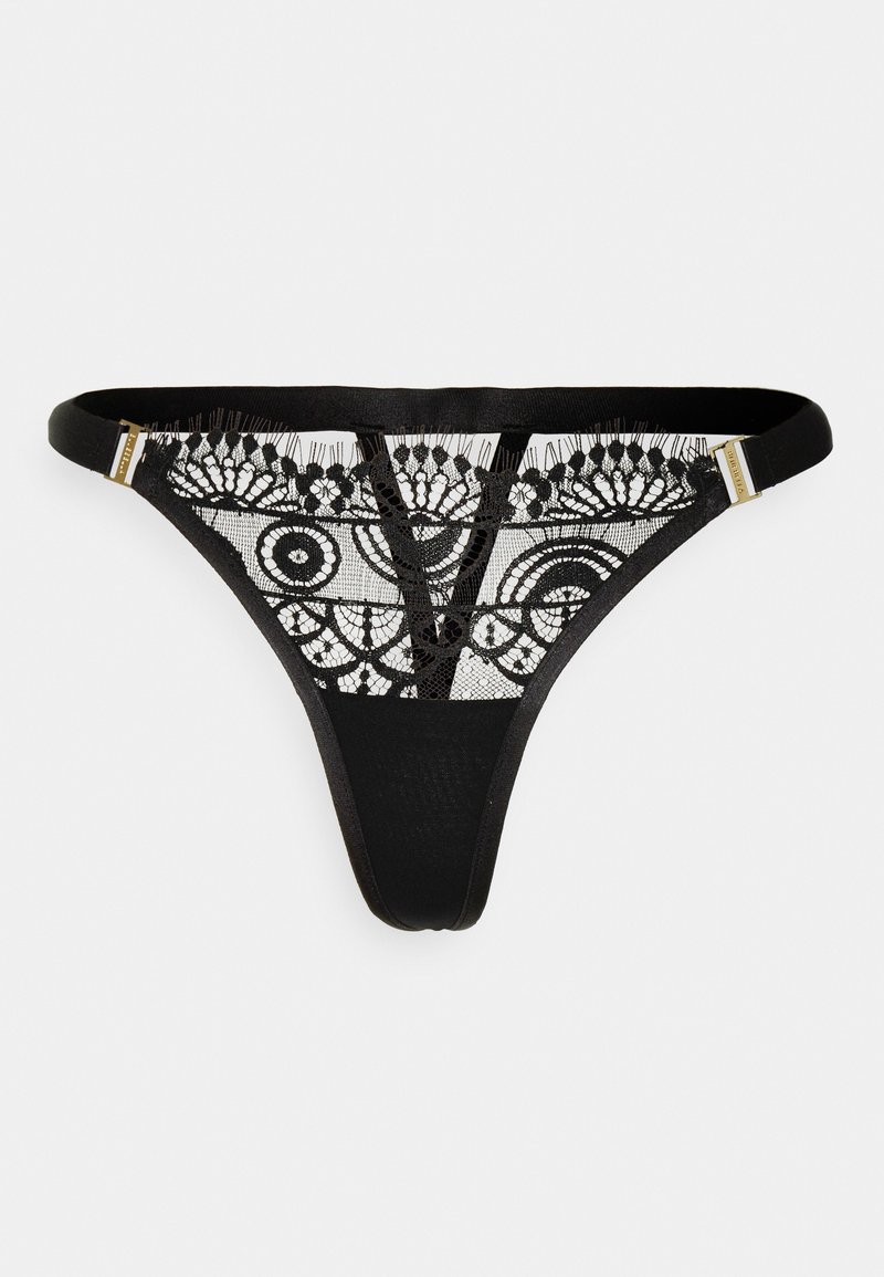 Tanga preta com painel de renda apresentando padrões circulares e detalhes delicados. Alças finas e acabamentos em tom dourado. Textura de tecido suave.