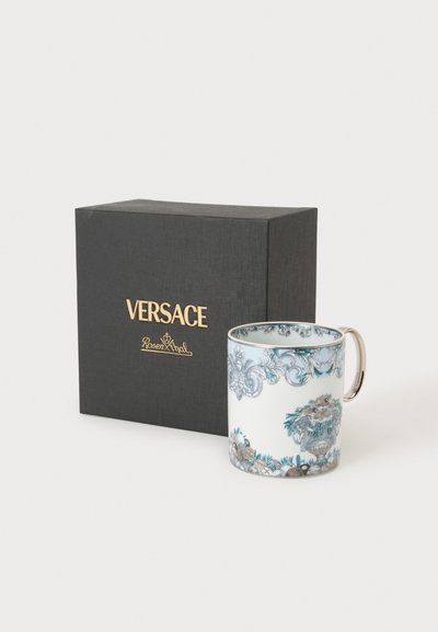Διακοσμητικό πορσελάνινο φλιτζάνι Versace με περίτεχνα μπλε και γκρι λουλουδάτα σχέδια και χρυσή λαβή, τοποθετημένο δίπλα σε μαύρο κουτί με την επωνυμία Versace.