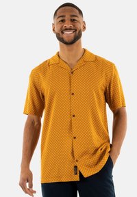 Korte mouw knopenblouse in levendig oranje met een ruitpatroon. Gemaakt van zachte stof met een kraag en bruine knopen.