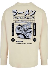 Šviesiai rudas ilgomis rankovėmis marškinėliai su juoda grafika, vaizduojančia rameną dubenį su animacinėmis akimis, lazdelių ir japonų kalbos tekstu ant nugaros.