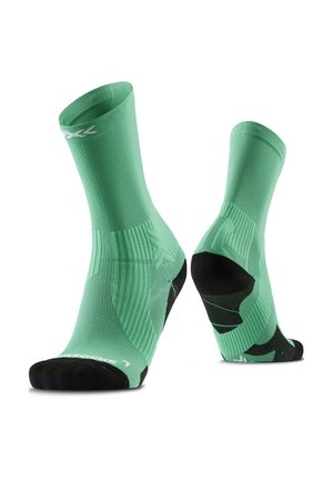 Groene atletieksokken met zwarte hiel- en teensecties, rechtop weergegeven om voor- en achterdetails te tonen.