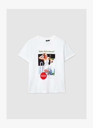 T-shirt en coton blanc arborant un graphisme vintage d'une femme tenant une bouteille de Coca-Cola. Le texte indique "Hello Refreshment." Manches courtes.