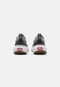 Sorte og grå sneakers med en teksturert semsket og mesh-overdel, hvit midtsåle og mønstret gummisåle. "ULTRARANGE" merkelapp på hælen.