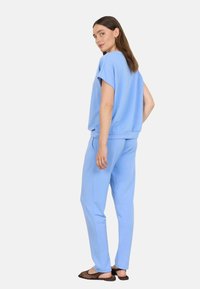 Light blue athletic set featuring a loose-fitting top with short sleeves and matching tapered pants, made from soft, textured fabric.