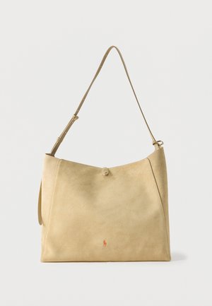 Bolso de hombro de ante beige con correa ajustable y pequeño logo naranja cerca del centro inferior, fondo liso.
