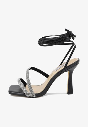 Sandali neri con tacco alto e punta quadrata, dotati di cinturini incrociati e un dettaglio decorativo di strass sul cinturino frontale. Lunghe fasce da legare alla caviglia.