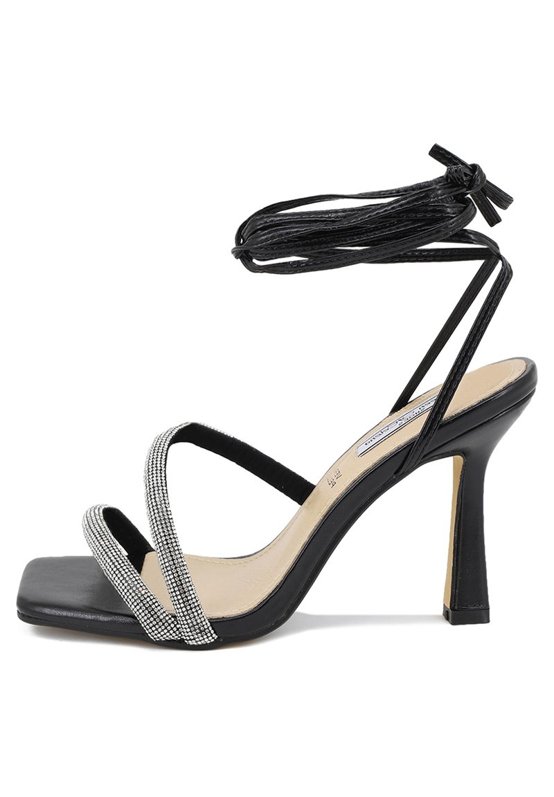 Sandali neri con tacco alto e punta quadrata, dotati di cinturini incrociati e un dettaglio decorativo di strass sul cinturino frontale. Lunghe fasce da legare alla caviglia.