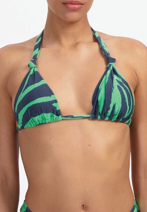 Kobieta w zielono-granatowym bikini w paski z wiązanymi na szyi ramiączkami na białym tle.