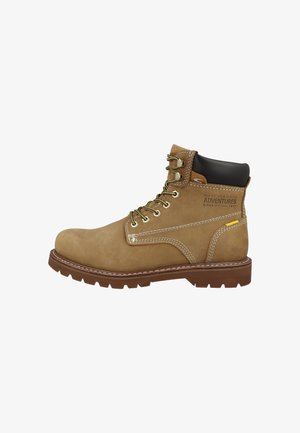 Tan suède enkellaarsjes met metalen oogjes, vetersluiting, rubberen zool, contrasterende stiksels en een zwarte gevoerde kraag.