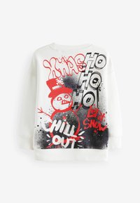 Vit sweatshirt med grafiskt tryck som föreställer en snögubbe, texten "XMAS", "CHILL OUT" och "LET IT SNOW" i röd och svart. Rund halsringning och avslappnad passform.