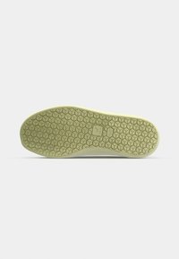 Semelle de chaussure avec un motif alvéolé de couleur beige clair, présentée sur un fond gris clair uni.