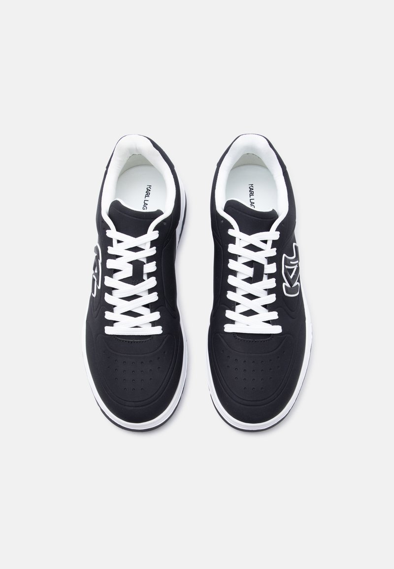 Par de zapatillas bajas negras con cordones blancos, suelas blancas y logo de la marca en el lateral, vistas desde arriba sobre un fondo blanco.