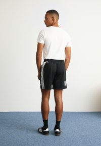 adidas Originals ADIDAS NTS RADIO ALLOVER PRINTED SUPERSTAR TRACK PANTS - Teplákové kalhoty - black