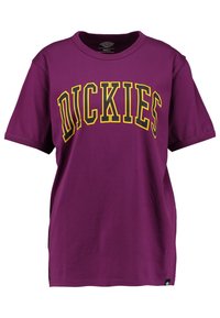 Camiseta de algodón morada con cuello redondo, mangas cortas y un gráfico en amarillo y negro que dice "DICKIES" impreso en el frente.