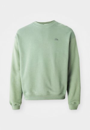 Lichtgroene crewneck sweatshirt met lange mouwen en een klein geborduurd krokodillenlogo op de linkerborst.