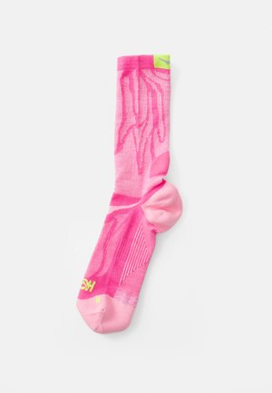 Chaussette de sport rose avec un motif texturé, talon et orteil renforcés, et accent de logo vert sur le bord. Présente une finition lisse.