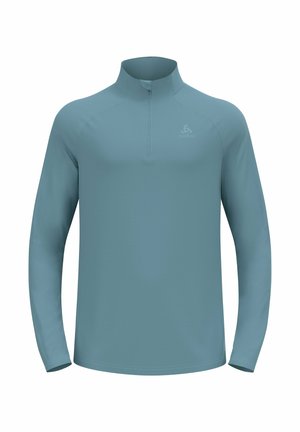 Light blue athletic half-zip long-sleeve top made from smooth, stretch fabric. Features a high collar and subtle logo detail on the chest.