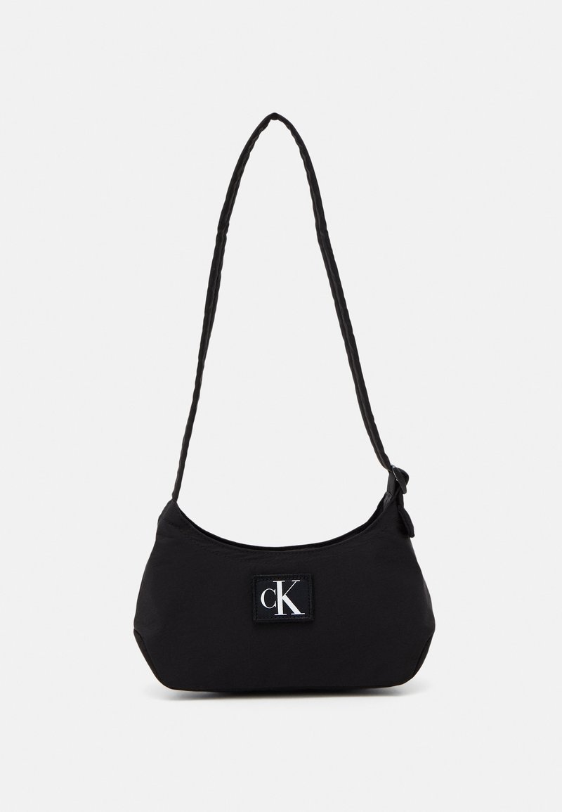 Borsa a spalla nera in nylon con una forma curva, tracolla intrecciata e un logo del marchio prominente su una toppa quadrata. Texture liscia, design minimale.