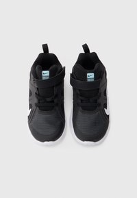 Μαύρα αθλητικά παπούτσια με υφασμάτινο δίχτυ, λευκή σόλα, λουρί Velcro και μπλε τόνους στη γλώσσα, διαθέτουν υφή σχεδίασης για καλύτερη πρόσφυση.